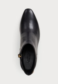 Black leather ankle boot with a pointed toe, smooth texture, and a gold hardware zipper accent on the side. Interior shows brand logo.