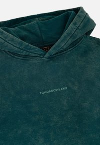 Capuchon sweatshirt in diep teal met een vervaagde textuur. Voorzien van "TOMORROWLAND" in lichtgroen op de voorkant.