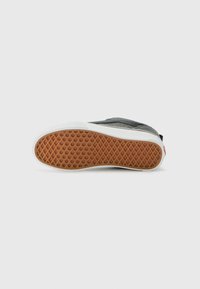 Sneaker sole in black rubber with a honeycomb texture, white edges, and light brown tread pattern. Features a simple and functional design.