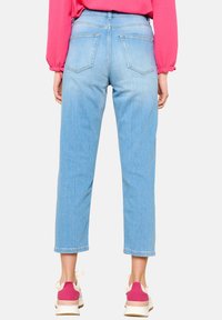 Vaqueros recortados de denim azul claro con pierna recta, que cuentan con dos bolsillos traseros y detalles de costura, combinados con zapatillas rosas y blancas.