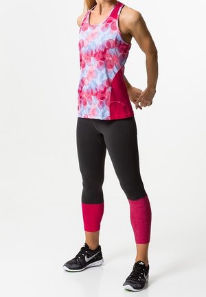 Top senza maniche con un motivo astratto blu e rosa e un pannello laterale rosa; abbinato a leggins neri e polsini con accenti rosa.