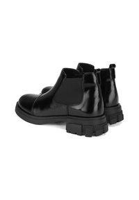 Bottines en cuir noir avec des panneaux élastiques sur les côtés, bouts ronds et semelles en caoutchouc épaisses. Texture lisse avec une finition brillante.