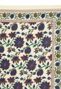 Tela estampada con flores grandes azules con detalles naranjas, rodeadas de hojas verdes sobre un fondo crema, bordeada con un ribete estampado.