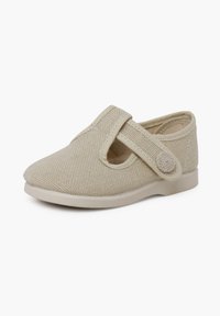 Chaussure beige pour tout-petit en tissu texturé, bout arrondi et bride ajustable avec fermeture par bouton sur fond blanc.