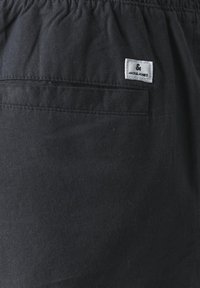 Black fabric shorts with an elastic waistband and a back pocket. Features a small white label with "JACK & JONES" logo.
