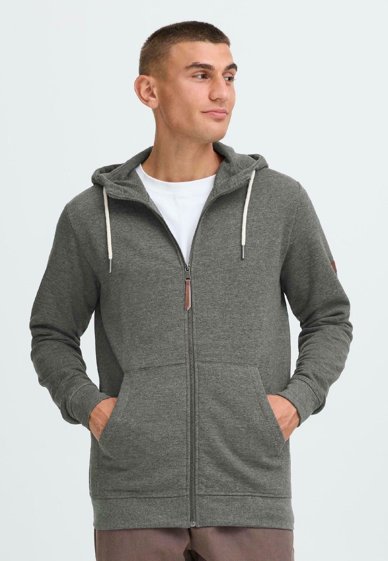 Grau Zip-Hoodie mit verstellbarem Kordelzug an der Kapuze, zwei Fronttaschen, gerippten Bündchen und Akzent aus Kunstleder am Reißverschluss.