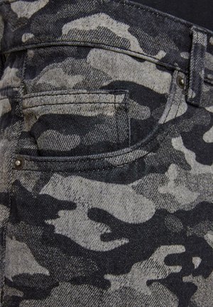 Black and gray camo denim fabric featuring a close-up of a pocket, with visible stitching and a silver metal button detail.