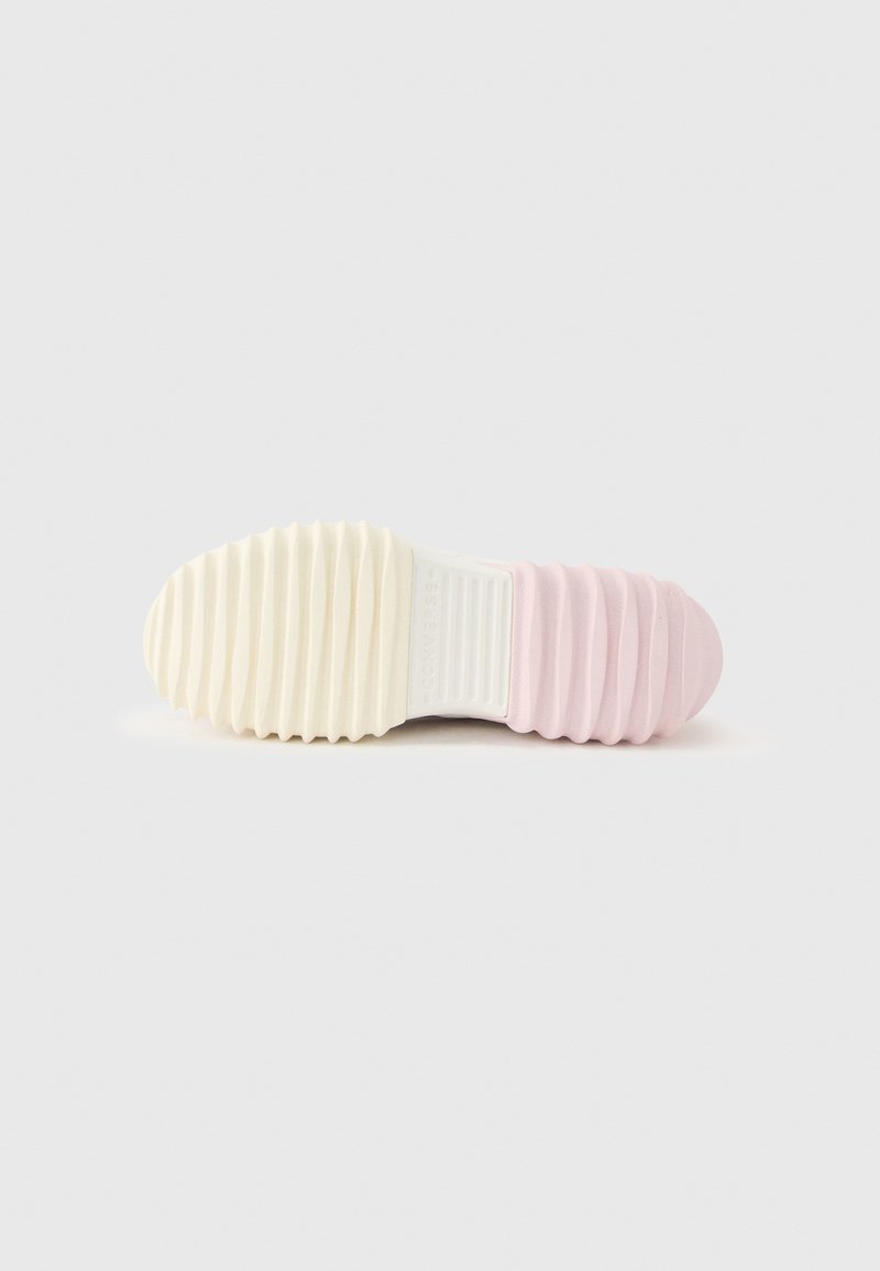 Shoe sole with textured grip, featuring cream-colored front and light pink ribbed heel, shown against a plain gray background.