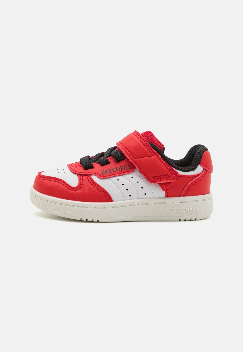 Sneaker rossa e bianca in materiale sintetico, con dettagli perforati, una fascia in velcro e accenti neri. Presenta una suola in gomma bianca.