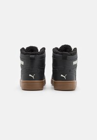Czarne sneakersy typu high-top z teksturowanym wykończeniem, futrzanym czarnym kołnierzem, brązowymi gumowymi podeszwami oraz białym logo Puma z tyłu.