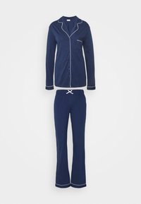 Navyblå pyjamasuppsättning gjord av mjukt tyg; knäpptopp med vit piping, långa ärmar och matchande byxor med elastisk midja och dragsko.