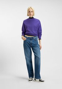 Paars cropped sweatshirt met ronde hals en geribde manchetten, gecombineerd met hooggeprofileerde blauwe denim jeans en zwart-witte sneakers.
