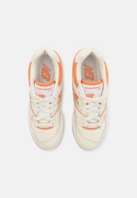 Adidași New Balance albaștri și portocalii cu un superior din piele netedă, accente perforate și șireturi albe. Prezintă logo pe limbă și pe lateral.