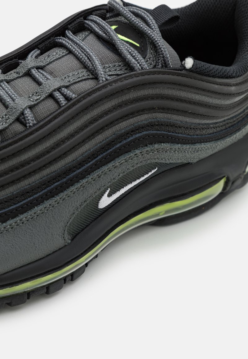 Sneaker Nike Air Max 97, z czarno-szarym schematem kolorów, wykonany z materiałów siateczkowych i skórzanych, o falistym wzorze i akcentach w limonkowej zieleni na jednostce powietrznej.