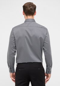 Zwart-wit gestreepte overhemden met een verspreide kraag, lange mouwen en knoopmanchetten, gedragen met zwarte broek.