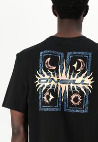 Black cotton t-shirt featuring a multicolored graphic on the back with stylized suns and moons, framed by geometric patterns.