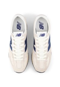 Αθλητικά παπούτσια με ταμπά επάνω μέρος από σουέτ, ναυτικές μπλε πλευρικές επισημάνσεις και λευκά κορδόνια. Διαθέτουν μαξιλαρωμένη γλώσσα και λογότυπο στην εσωτερική σόλα. Στρογγυλή σχεδίαση μύτης.