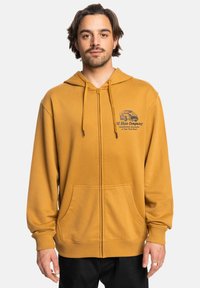 Geel zip-up hoodie van zacht materiaal, voorzien van een voorlogo, een capuchon met trekkoord en twee voorzakken. Geribbelde manchetten maken het ontwerp compleet.