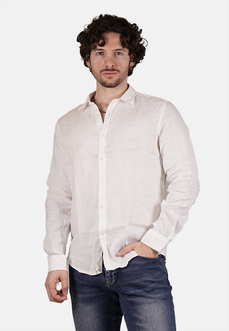 Camicia bianca in lino a maniche lunghe con polsini a un bottone, pattina frontale con bottoni e una vestibilità comoda. Indossata con jeans scuri.