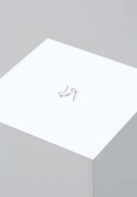 Srebrn prstan iz zvitega žičnega materiala z obliko tekočih, valovitih linij. Postavljen na svetlem ozadju s gladkim, sijajnim zaključkom.