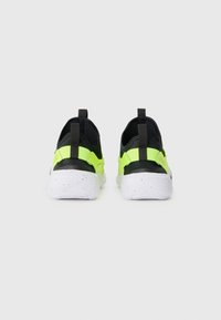 Chaussures de sport noires et vert fluo avec une tige texturée, semelle blanche tachetée, languettes au talon et un design épuré.