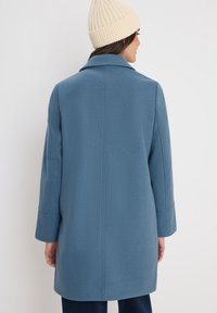Abrigo de mezcla de lana azul con cuello, mangas largas y corte recto. Presenta un diseño de costura trasera limpio y una textura suave.