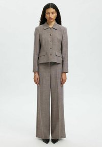 Completo marrone polveroso su misura con giacca colletto e chiusura con bottoni, due tasche frontali e pantaloni a gamba larga, realizzato in un tessuto textures.