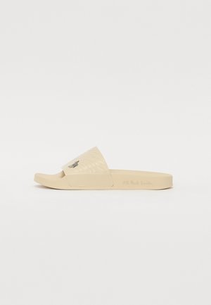 Beige schuif sandalen met een gestructureerde band en een geborduurd ontwerp. De zool is plat en licht gevormd voor comfort.