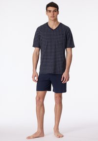 Navy blue V-neck t-shirt with a grid pattern in beige, paired with solid navy shorts, featuring short sleeves and a relaxed fit.