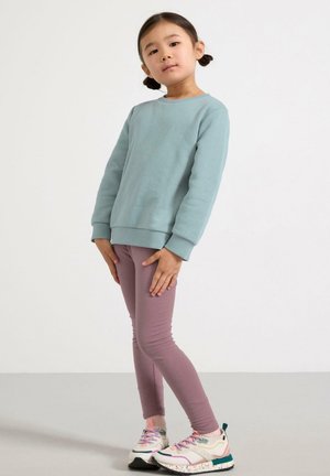 Lyseblå sweatshirt med rund hals, kombineret med pink leggings og multikolore sneakers med en marmorert sål. Glat struktur.