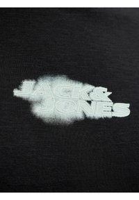 Μαύρο ύφασμα με λευκό σύννεφο-όμοιο μοτίβο και το κείμενο "JACK & JONES" τυπωμένο με έντονα κεφαλαία γράμματα.