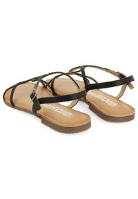 Sandalias negras de tiras con detalles trenzados y una correa de tobillo ajustable, que presentan una suela marrón claro con costuras sutiles y un logo.