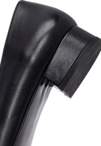 Scarpa nera in pelle con tacco, caratterizzata da una finitura lucida, punta arrotondata e tacco alto robusto con suola in gomma testurizzata per una migliore aderenza.
