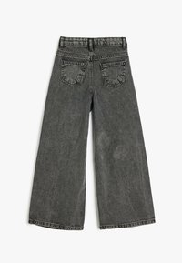Jean en denim noir à jambes larges avec une texture légèrement décolorée, présentant deux poches arrière et un design classique à cinq poches.