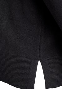 Zbliżenie czarnej dzianiny z prążkowanym dołem i małym centralnym rozcięciem po boku.