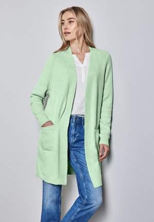 Mint green cardigan made of soft fabric, open front design with two front pockets, worn over a white henley shirt and blue jeans.