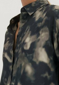 Gestreepte overhemd in donkere tinten blauw en grijs, met een zachte stof en een vervaagd, abstract patroon, en een klassieke kraagontwerp.