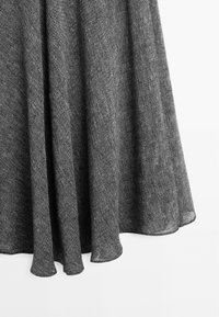 Tessuto grigio testurizzato con un sottile motivo intrecciato, che si drappeggia in modo fluido e termina con un orlo arrotondato. Materiale morbido e leggero.