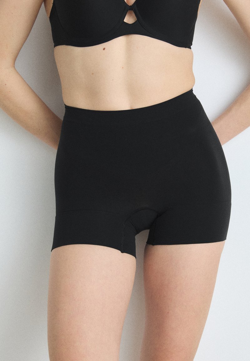 Sorte høytalede shorts i et jevnt, elastisk stoff. Har en tettsittende design med midt på låret lengde og en sømløs finish.