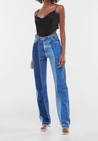 Blauwe denim jeans met een kleurblokontwerp dat lichte en donkere tinten bevat, recht gesneden pasvorm, hoog in de taille en franjes aan de zoom.