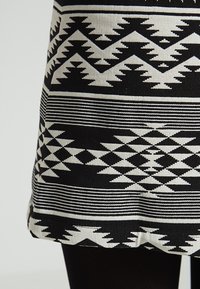 Gonna a righe in bianco e nero con motivi geometrici e frecce, realizzata in materiale knit testurizzato.