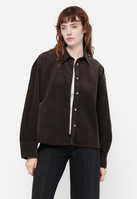 Cămașă overshirt din catifea brown cu guler, nasturi frontali și mâneci lungi. Textură netedă cu un croi lejer.