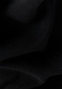 Gros plan d'un tissu tricoté noir montrant la texture et des plis délicats.
