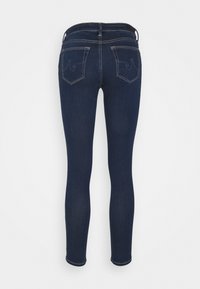 Tmavě modré skinny džíny s hladkým povrchem, vybavené dvěma zadními kapsami s prošívanými detaily a klasickým designem pasu.