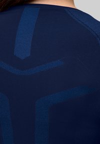 Granatowa koszulka sportowa z teksturowanym wzorem i jaśniejszymi niebieskimi akcentami, dopasowany krój podkreślający wydajność i wygodę.