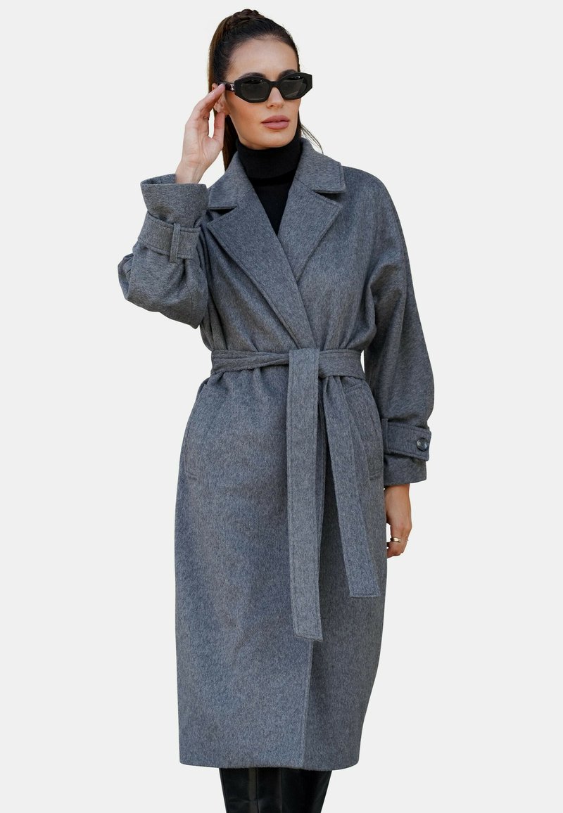 Szary płaszcz trench z wełny z domieszką, z paskiem w talii, dużym kołnierzem i zapinanymi mankietami, o luźnym kroju i minimalistycznym designie.