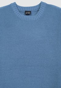 Jasnoniebieski sweter dzianinowy z prążkowanym okrągłym dekoltem. Teksturowany splot na całej powierzchni, z metką z logo wewnątrz kołnierza.
