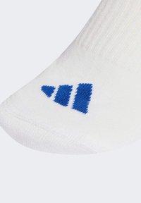 Biała bawełniana skarpeta z niebieskim paskiem na palcu, prążkowaną teksturą i wzmocnionym szwem dla większej trwałości.