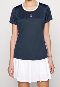 Tmavě šedé sportovní tričko s krátkými rukávy, kulatým výstřihem a bílými akcenty. Obsahuje malé logo na prsou a má hladkou texturu.