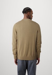 Beige knitted sweater with long sleeves and a ribbed hem. The back features a simple design with a round neckline and regular fit.
